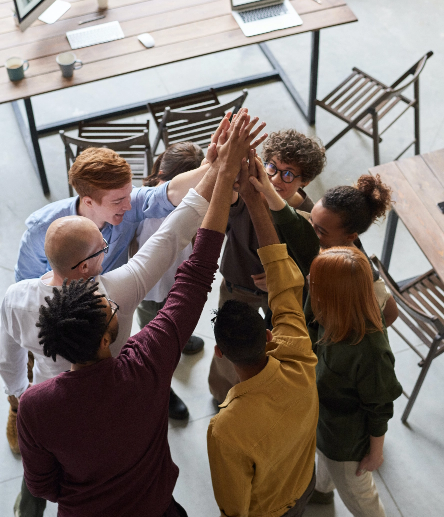 Diverse team members celebrating with hands raised in a collaborative workplace setting.