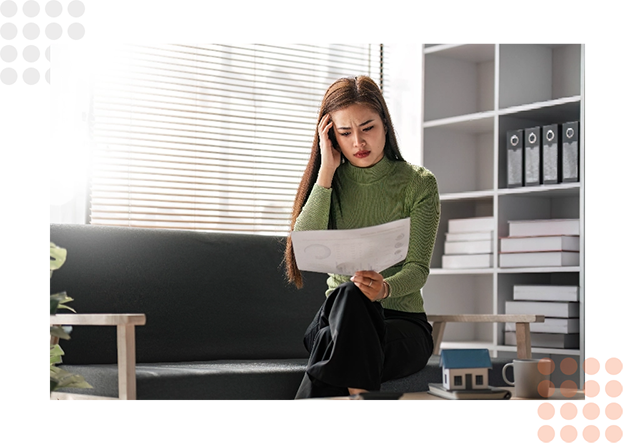 A woman reads documents while seated in a well-lit office with shelves behind her.