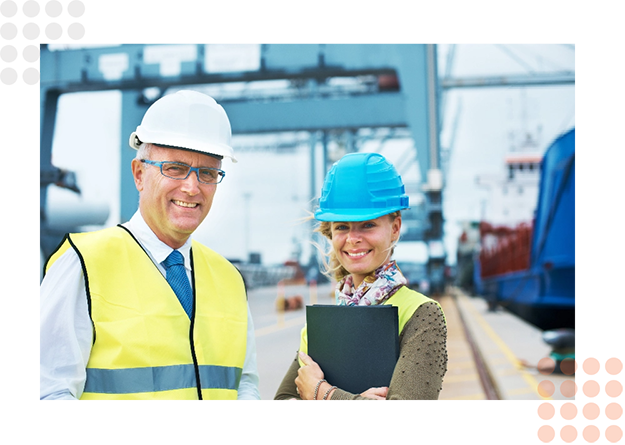 Two professionals in safety gear discuss logistics at a warehouse.