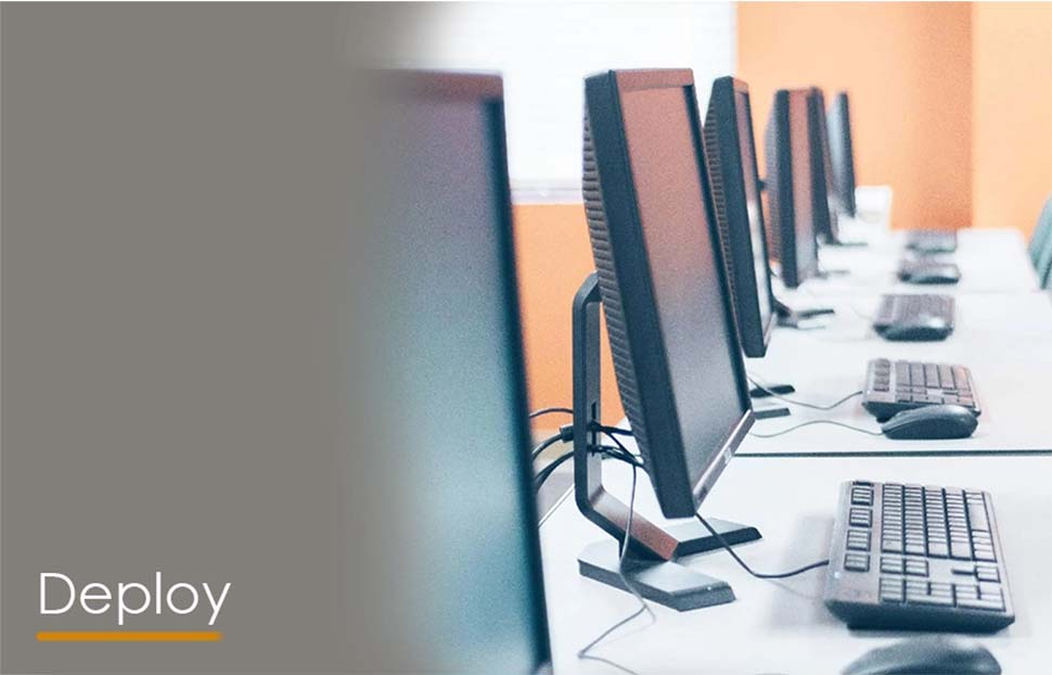 Row of computers on desks in a modern office setting, ready for deployment.