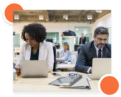 A woman and a man working on laptops in a modern office during user acceptance testing.