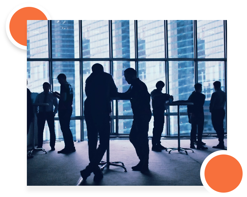 Silhouettes of a group discussing at a table in a bright office with large windows.