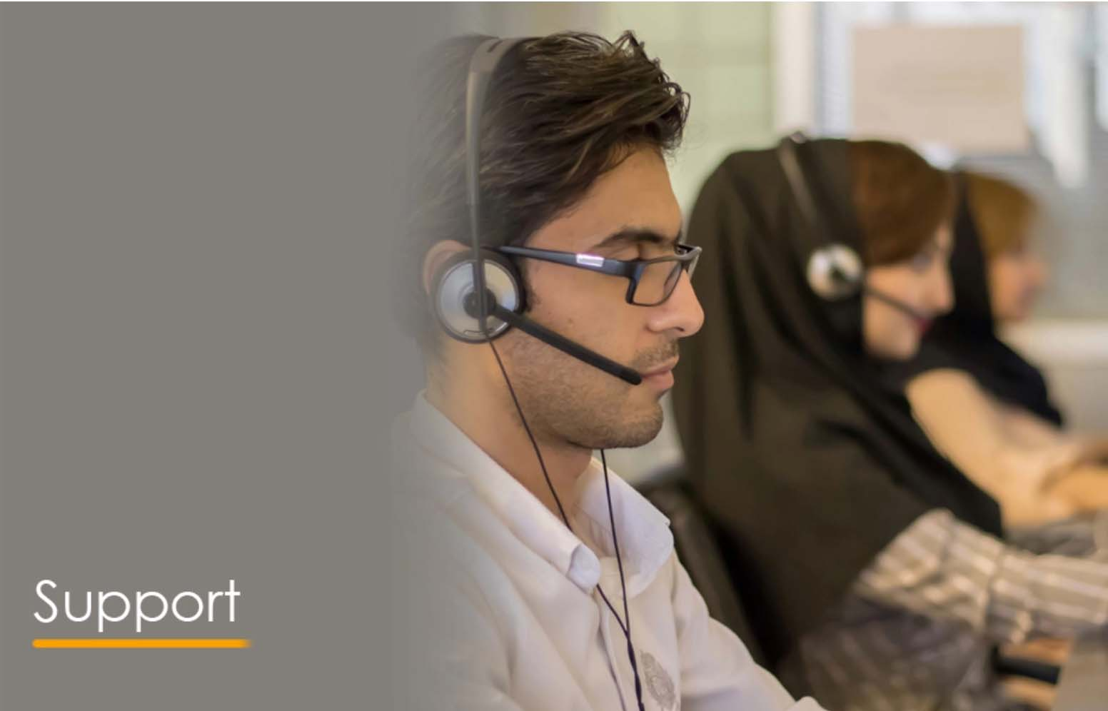 A man wearing a headset in an office, assisting customers with support services.