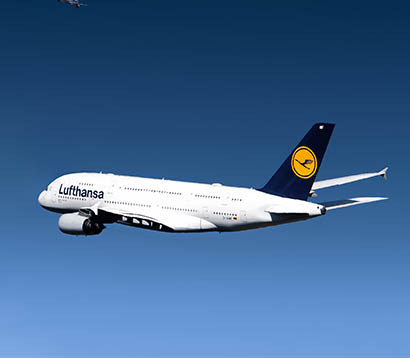 Lufthansa airplane flying against a clear blue sky, representing air travel and logistics.